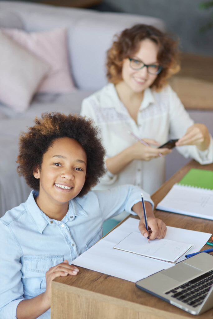 Élève souriante en cours à distance, regardant la caméra