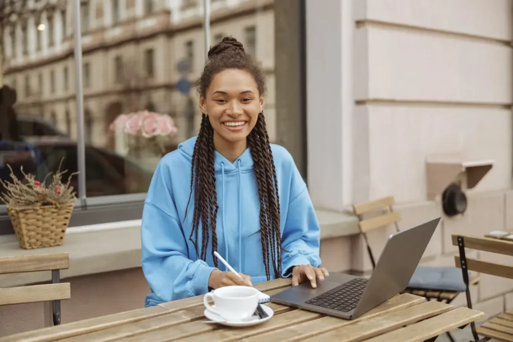 Jeune femme souriante travaillant sur un ordinateur portable dans un café