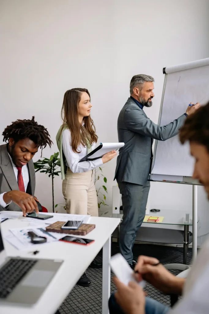 Un professionnel accompagne une équipe dans la structuration d’un projet, illustrant l’expertise humaine dans la création d’organisme de formation.